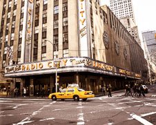 A wall art photo of a yellow taxi going by Radio City Hall in New York